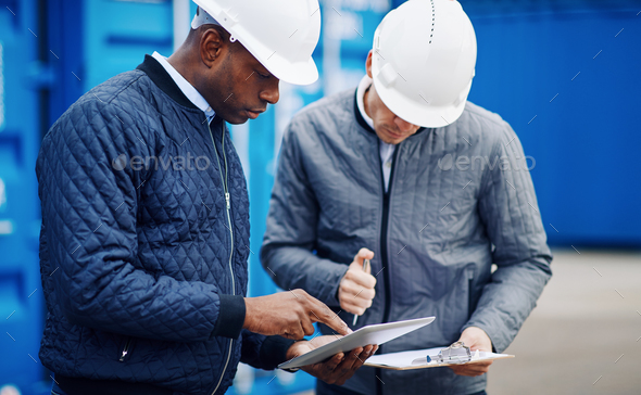 Two engineers comparing inventory lists together in a shipping yard - Stock Photo - Images