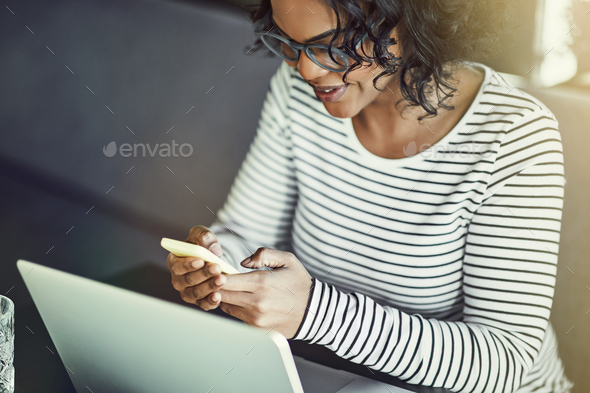 Young African woman using a laptop and reading text messages - Stock Photo - Images