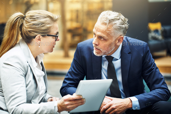 Mature colleagues discussing business together in an office lobby - Stock Photo - Images