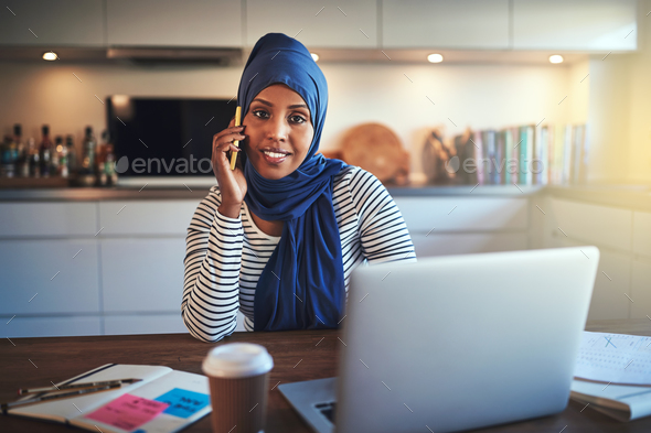 Young Arabic female entrepreneur talking on a cellphone at home - Stock Photo - Images