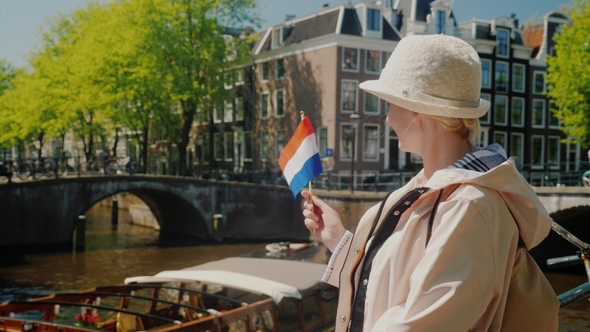 A Woman with the Flag of the Netherlands in Her Hand Admires the Beautiful View of the Canal in alt