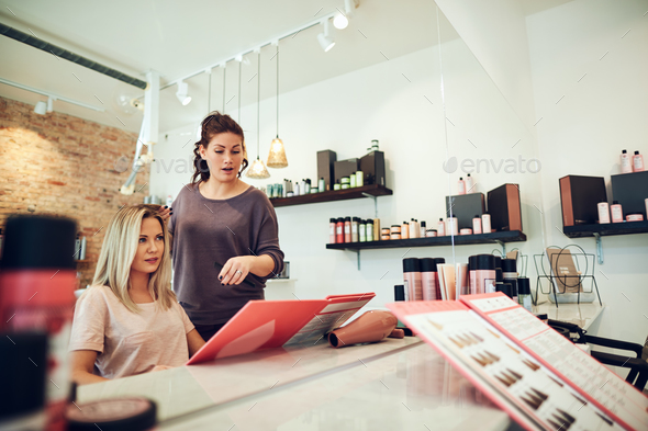 Client and stylist choosing hair dyes during a salon appointment - Stock Photo - Images