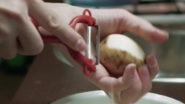 Women's Hands Peel Potatoes