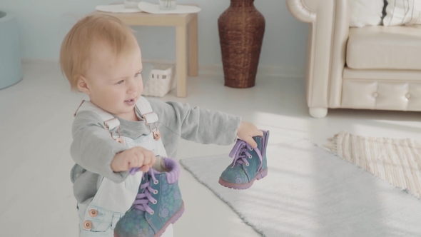 Little Lovely Girl Takes Her Shoes. Happy Beautiful Baby Gives Her Shoes To Her Mom.