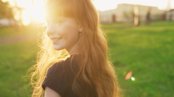 Happy Ginger Girl Walking and Looking Into Camera at Sunset in Summer Park