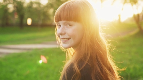 Happy Girl with Red Hair Walking, Looking Into Camera and Smiling at Sunset