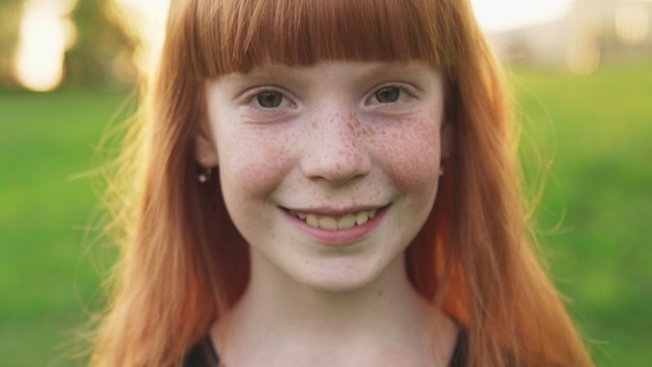Face of Happy Ginger Girl with Freckles on Blurred Background