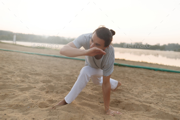 Athletic capoeira performer making movements on the beach - Stock Photo - Images