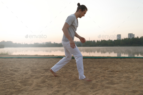 Athletic capoeira performer making movements on the beach - Stock Photo - Images
