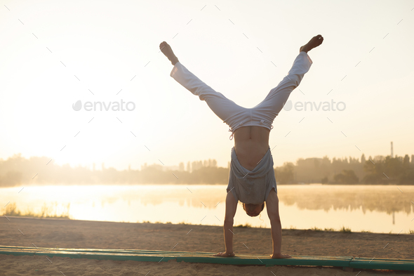 Athletic capoeira performer workout training on the beach sunris - Stock Photo - Images