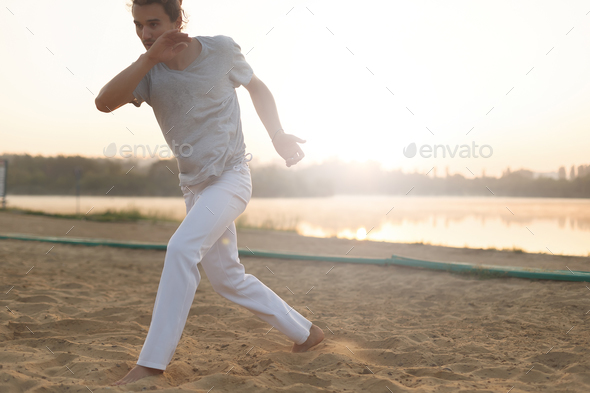 Athletic capoeira performer making movements on the beach - Stock Photo - Images