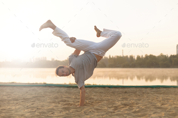Athletic capoeira performer workout training on the beach sunris - Stock Photo - Images