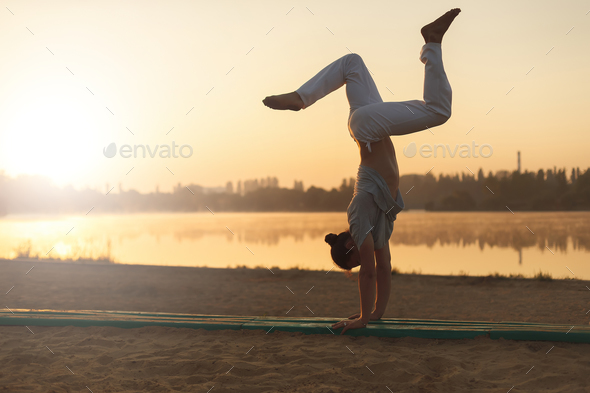 Athletic capoeira performer workout training on the beach sunris - Stock Photo - Images