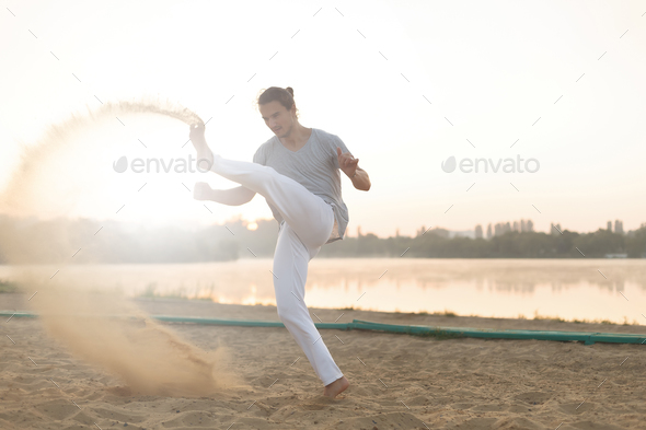 Athletic capoeira performer workout training on the beach sunris - Stock Photo - Images