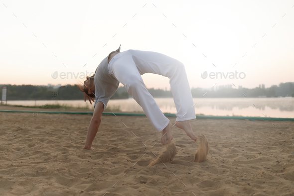 Athletic capoeira performer workout training on the beach sunris - Stock Photo - Images