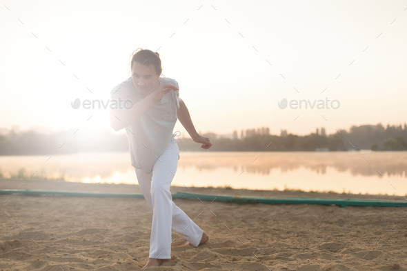 Athletic capoeira performer making movements on the beach - Stock Photo - Images
