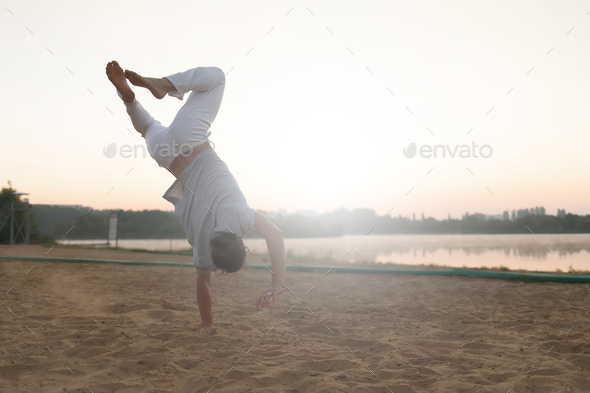 Athletic capoeira performer workout training on the beach sunris - Stock Photo - Images
