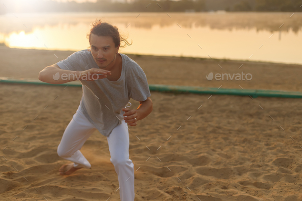 Athletic capoeira performer making movements on the beach - Stock Photo - Images