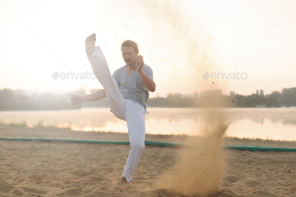 Athletic capoeira performer workout training on the beach sunris - Stock Photo - Images