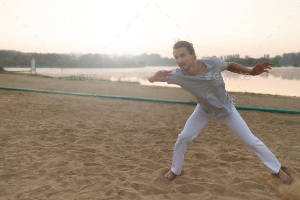 Athletic capoeira performer making movements on the beach - Stock Photo - Images
