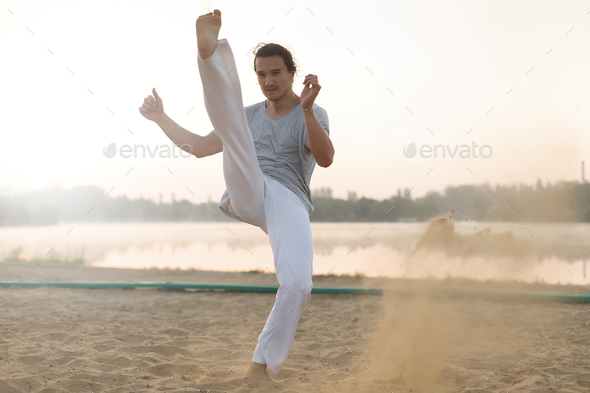 Athletic capoeira performer workout training on the beach sunris - Stock Photo - Images