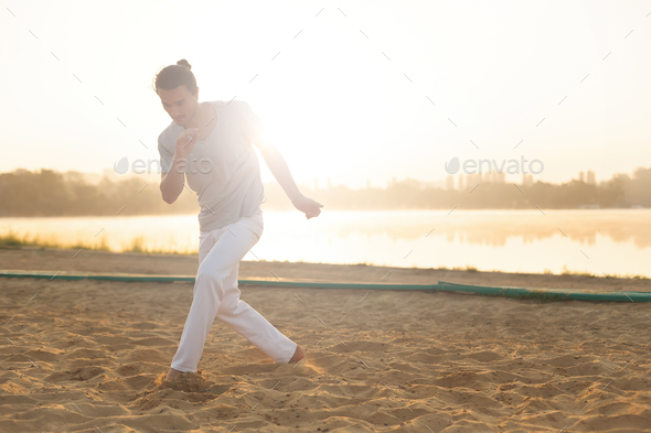 Athletic capoeira performer making movements on the beach - Stock Photo - Images