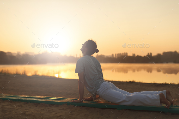 Young athletic men doing yoga on the sand in the park - Stock Photo - Images