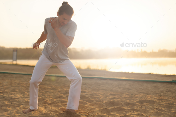 Athletic capoeira performer making movements on the beach - Stock Photo - Images