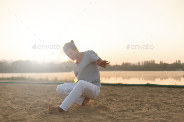 Athletic capoeira performer making movements on the beach - Stock Photo - Images