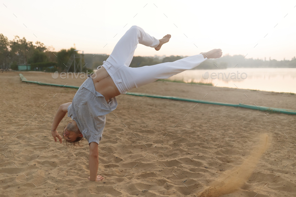Athletic capoeira performer workout training on the beach sunris - Stock Photo - Images