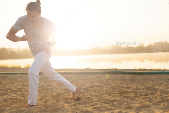 Athletic capoeira performer making movements on the beach - Stock Photo - Images