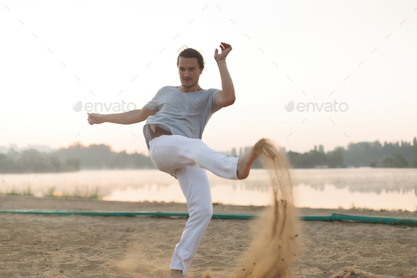 Athletic capoeira performer workout training on the beach sunris - Stock Photo - Images