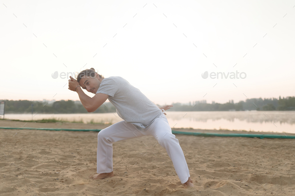 Athletic capoeira performer making movements on the beach - Stock Photo - Images
