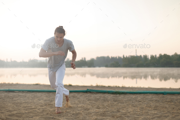 Athletic capoeira performer making movements on the beach - Stock Photo - Images