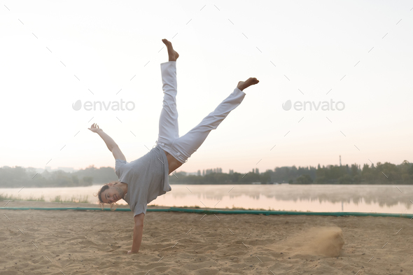 Athletic capoeira performer workout training on the beach sunris - Stock Photo - Images
