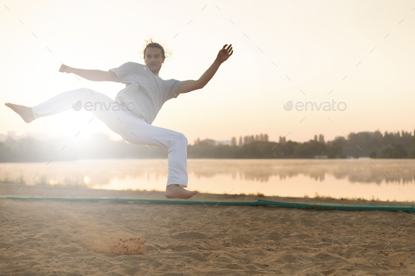 Athletic capoeira performer workout training on the beach sunris - Stock Photo - Images