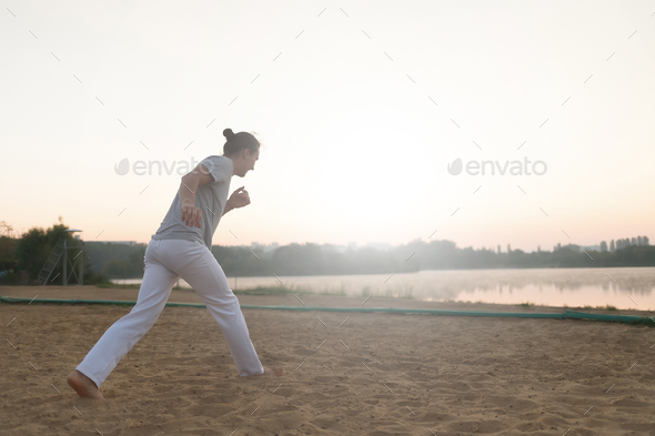 Athletic capoeira performer making movements on the beach - Stock Photo - Images