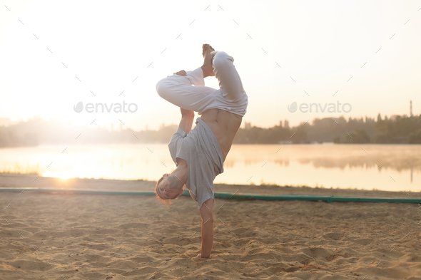 Athletic capoeira performer workout training on the beach sunris - Stock Photo - Images