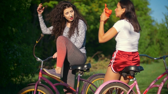 Rest on a Bike Ride, Two Female Cyclists Drink Water and Talk, Sunny Summer Day alt
