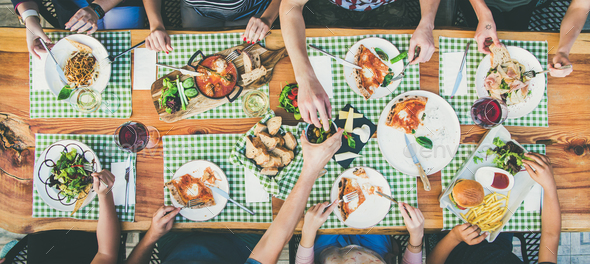 eating and leisure concept - group of people having dinner at table with food - Stock Photo - Images