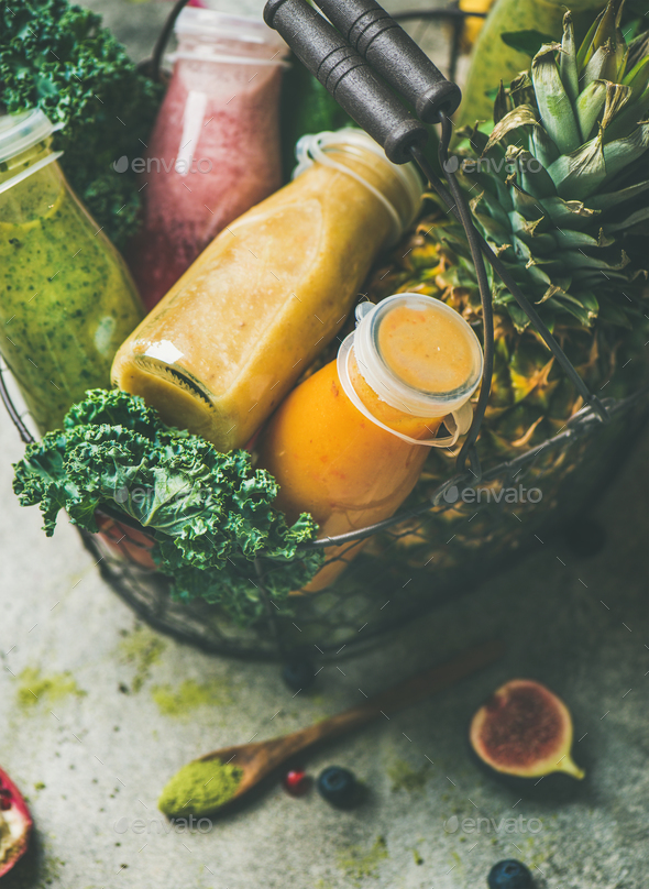 Colorful smoothies in bottles with fruits in basket, grey background - Stock Photo - Images