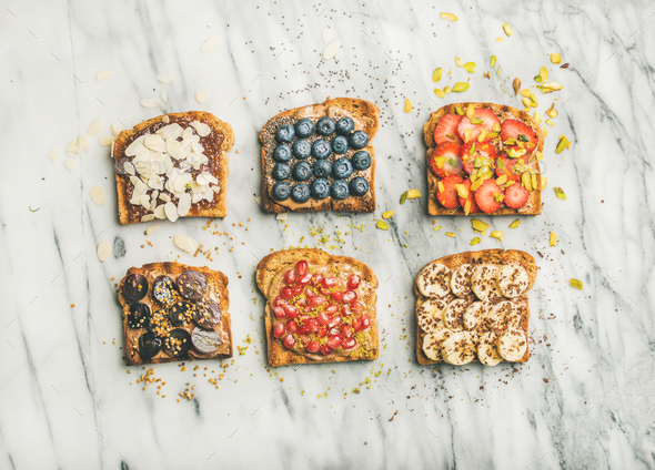 Vegan whole grain toasts with fruit, seeds, nuts, peanut butter - Stock Photo - Images