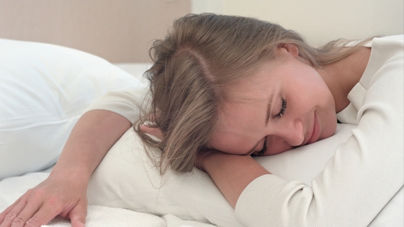 Relaxed Young Blonde Girl Sleeping on White Bed at Home or in Hotel Room alt