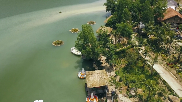 Bungalows with Thatched Roof and Wooden Pier for Boats on Shore Green Lake in Luxury Mountain Hotel alt