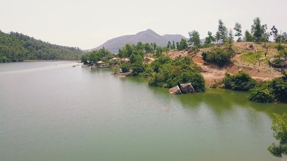 Exotic Bungalows with Thatched Roof and Boat Pier on Shore Mountain Lake in Luxury Hotel Aerial View