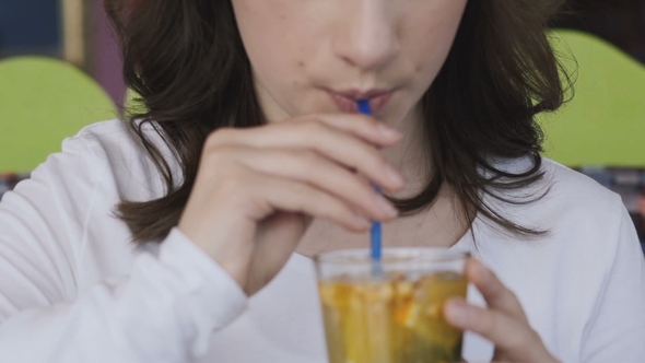 View of Girl Stirs and Drinks Lemonade with Tubule in Cafe alt