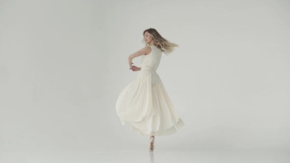 Ballerina in a Light Studio Dances in Pointe Shoes. Ballet Dancer in a Light Fluttering Long Dress alt