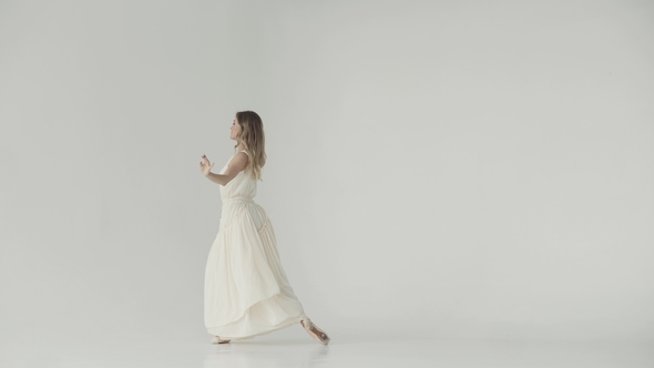 Ballerina in a Light Studio Dances in Pointe Shoes. Ballet Dancer in a Light Fluttering Long Dress alt