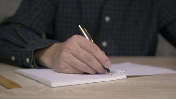 Man Studying and Writing in Copybook with Pen alt