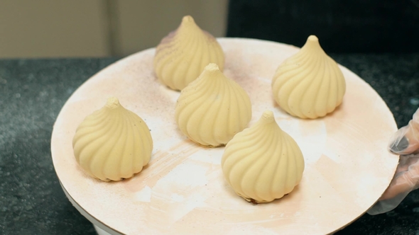 of Five Meringue Pastries Being Painted By Confectioner. alt
